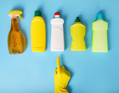 Hand in gloves choosing cleaning product on blue background