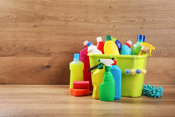 Cleaning products in bucket on wood background