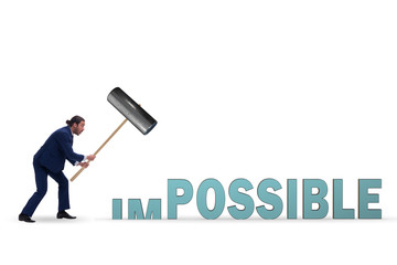 Businessman hitting the word impossible with hammer