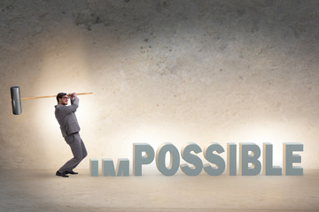 Obraz premium Businessman hitting the word impossible with hammer