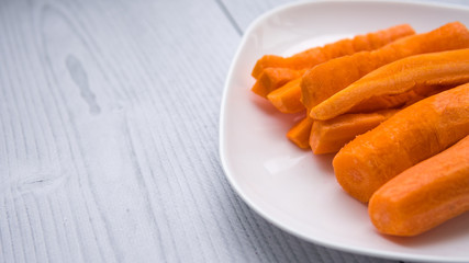 Slices of fresh carrots on a white plate. Isolated on white wooden vinyl background