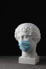 Medical mask on an antique statue. Virus epidemic medical care