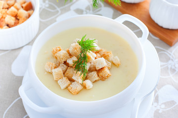 Mashed potato soup with homemade croutons in a white soup plate, horizontal