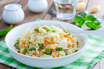 Italian risotto with vegetables - peas, beans, carrots, peppers on a white plate, selective focus