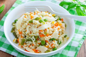 Italian risotto with vegetables - peas, beans, carrots, peppers on a white plate, selective focus