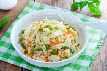 Italian risotto with vegetables - peas, beans, carrots, peppers on a white plate, selective focus