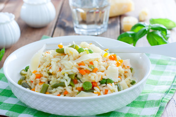 Italian risotto with vegetables - peas, beans, carrots, peppers on a white plate, selective focus