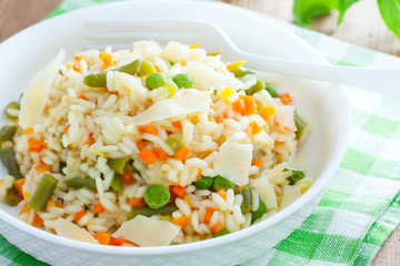 Italian risotto with vegetables - peas, beans, carrots, peppers on a white plate, selective focus