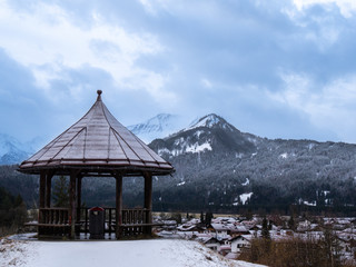 The wooden gazebo on the view platform over the Oberstdorf with mountains in background.