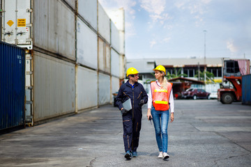 Foreman and worker staff wearing a yellow helmet walking in a industrial shipping yard. He's...