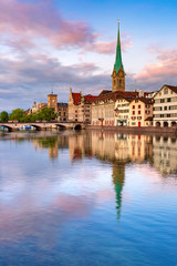 Obraz premium Famous Fraumunster church with reflections in river Limmat at pink sunrise in Old Town of Zurich, the largest city in Switzerland