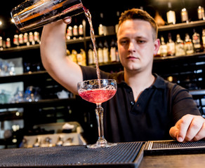 Bartender is making cocktail at bar counter. Fresh cocktails. Barman at work
