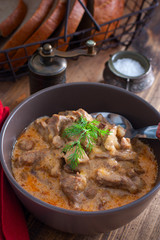 Traditional beef stroganoff in a ceramic bowl on a wooden table, selective focus