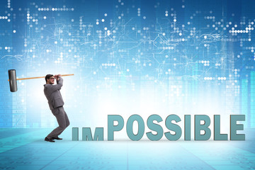 Businessman hitting the word impossible with hammer
