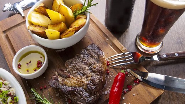Bifes de churrasco em t&aacute;bua de madeira com acompanhamentos