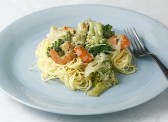 Creamy pasta with broccoli and shrimp on a blue plate with a fork