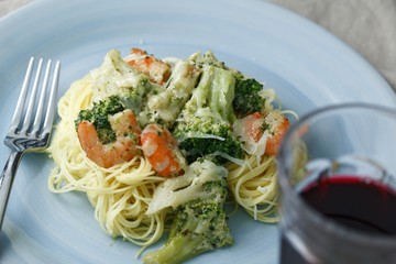 Creamy pasta with broccoli and shrimp and a glass of red wine