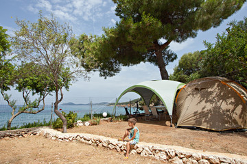 Boy in front of a tent in sea camping
