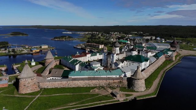Smooth cinematic flyby of the Solovetsky monastery from the side of the Holy Lake with a view of the White Sea on a clear sunny day. Solovetsky monastery is an old (1420) ROC monastery.