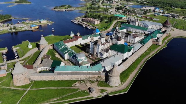 Smooth cinematic flyby of the Solovetsky monastery from the side of the Holy Lake with a view of the White Sea on a clear sunny day. Solovetsky monastery is an old (1420) ROC monastery.