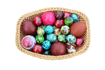 Basket of straws with Easter eggs painted in different colors and different sizes  on an isolated white background