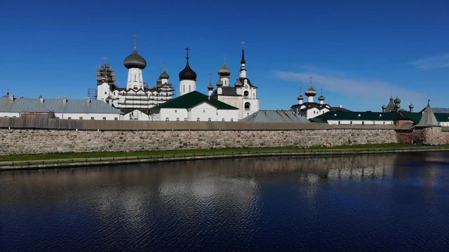 Smooth cinematographic shooting of the Solovetsky monastery from the side of the Holy Lake almost from the surface of the water on a clear sunny day.