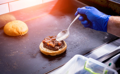 Chef preparing burgers at the kitchen grill stove. Restaurant.