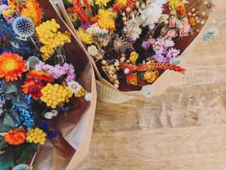 Vibrant dried flower arrangement in red, yellow and purples on a wooden background