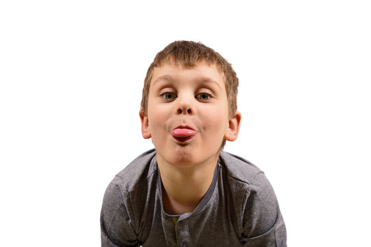 A small cheerful boy shows his tongue to the camera on a white background