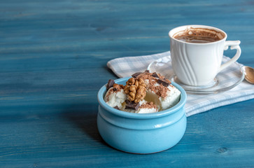 Ice cream with chocolate and walnuts, a cup of coffee on a blue wooden table.