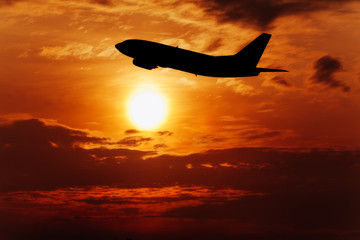 Fototapeta na wymiar Airplane fly on sunset sky. Airplane in the sky at sunrise