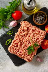 Mince. Fresh raw minced beef on cutting board and ingredients for cooking on a stone or slate table. Top view flat lay.