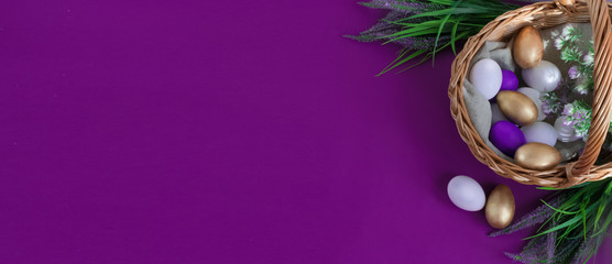 Happy Easter Day.Greeting card or banner for sale of a store or website.Golden, white, purple eggs in a basket on a purple background next to a bouquet of greenery.Provence.Copy space.Top view