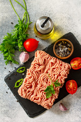 Mince. Fresh raw minced beef on cutting board and ingredients for cooking on a stone or slate table. Top view flat lay.