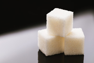 Three pieces of sugar on black glass, close-up