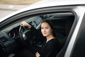 Fototapeta na wymiar Young woman in a driving school, learning to drive, sitting in a car, smiling