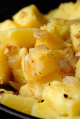 Freshly fried potatoes with onions in a pan closeup. Shallow depth of field