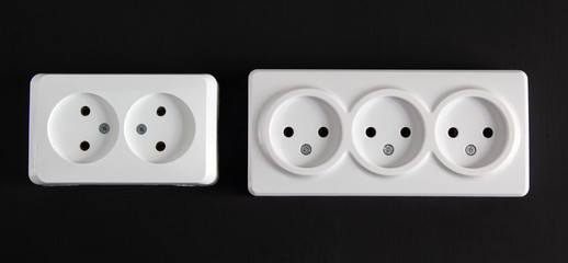 Two bright rectangular sockets lying side by side in a horizontal position on a black background.