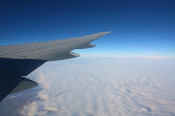 Obraz na płótnie Canvas Jet airplane wing illuminator view. Blue sky