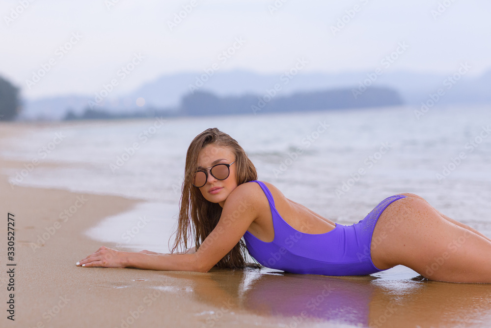 Wall mural beautiful slim girl in a blue swimsuit on the ocean.