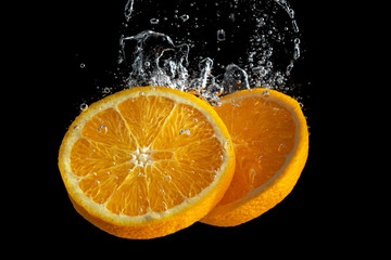 Fototapeta na wymiar Fresh sliced orange fruit in water splash isolated on black background. Minimal food concept.
