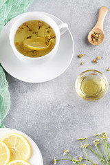 herbal chamomile tea, honey, lemon and fresh daisy flowers on blue background