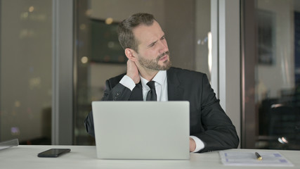 The Tired Young Businessman having Neck Pain at Night