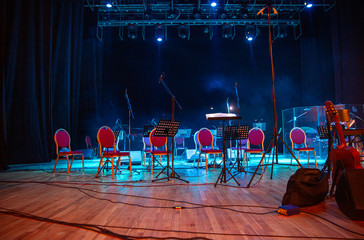 Music stands, microphones, musical instruments and chairs at concert stage