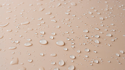 Lots of different rain water drops on a beige background, top view