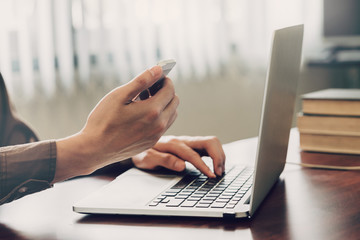 business man hand texting laptop and holding phone on wooden table