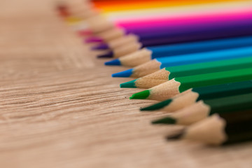 A number of colored pencils in a row on wooden background. Colorful photograpphy. Selected focus on green.