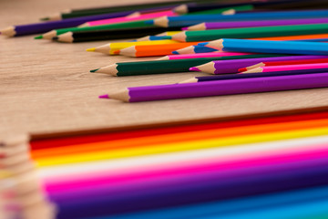 Obraz premium A number of colored pencils scattered on wooden background. Colorful photograpphy. Selected focus.