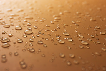 Many transparent drops of rain water on an orange background