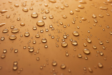 Many transparent drops of rain water on an orange background